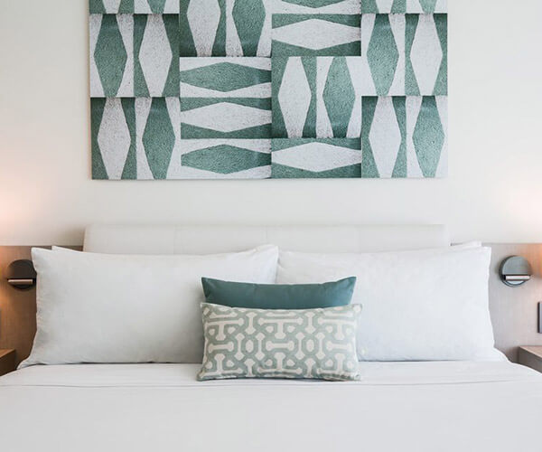 King bed feature with geometric-patterned throw pillows and artwork