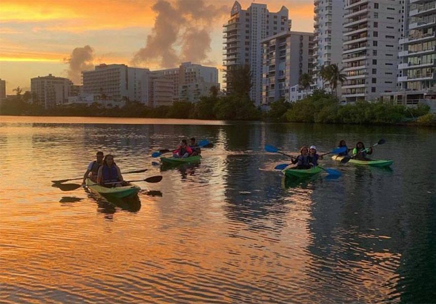 A group of people kayaking on the ocean during sunset