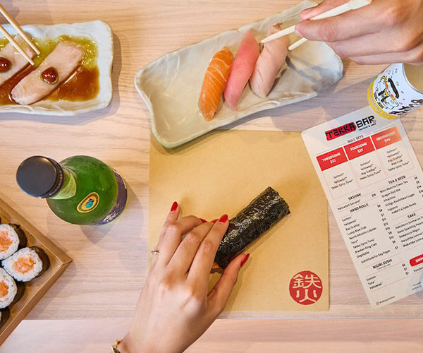 Couple eating sashimi, temaki hand rolls, nigiri sushi, and maki rolls with drinks