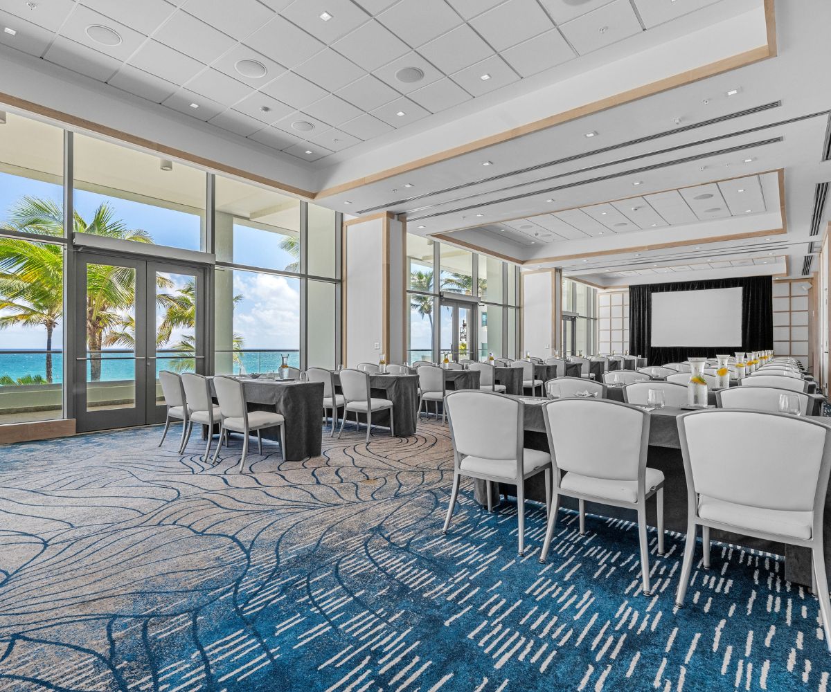 A meeting room with white chairs and tables and ocean view