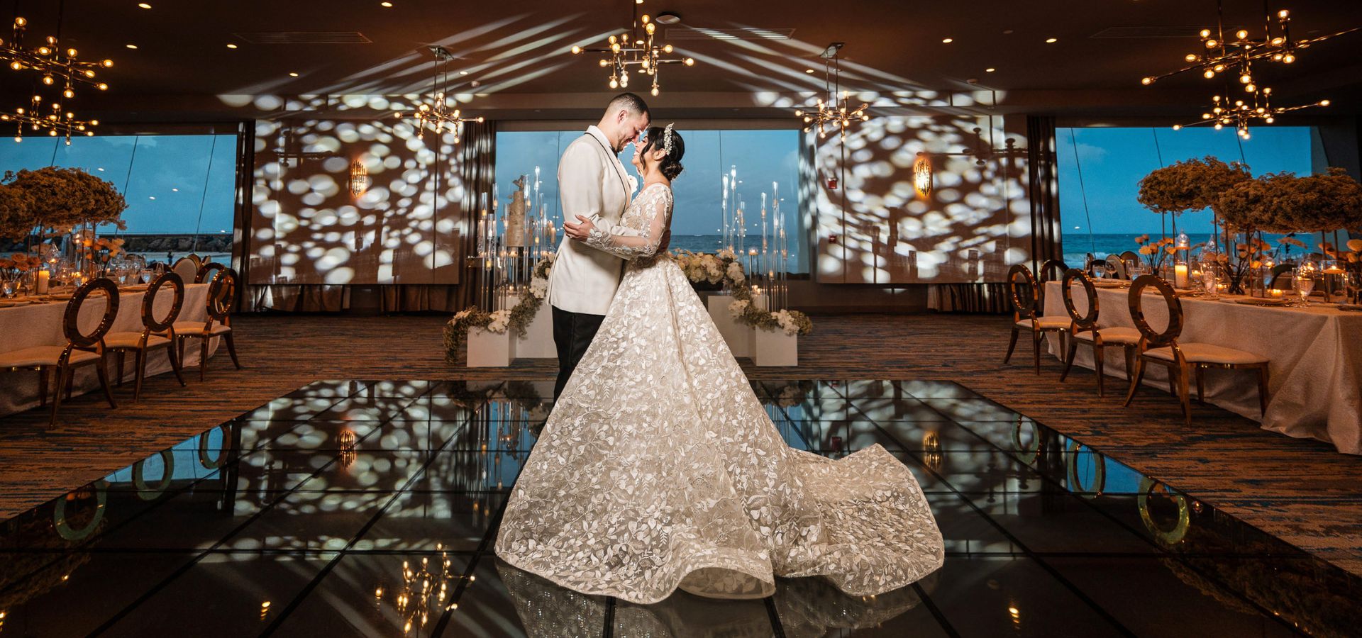 A couple dancing in a room with lights and the ocean view