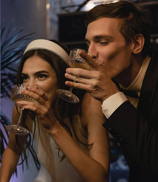 Bride and groom drinking together out of coupe glasses