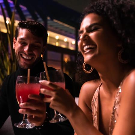 Couple holding cocktails smiling at night