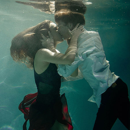 Couple kissing underwater in formal clothing