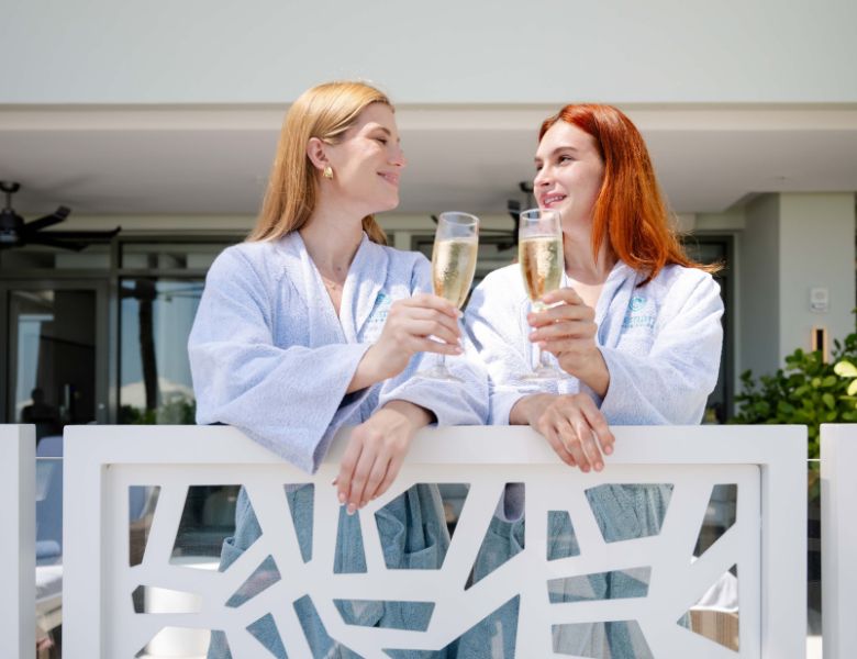 two women cheering with champagne at the spa balcony