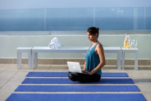 woman working on laptop while doing yoga outdoors